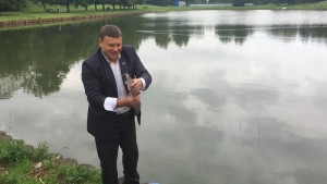 Депутат Сергей Жабин выпускает рыбу в пруд 